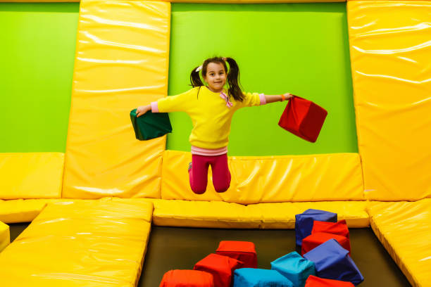 felice infanzia di un bambino moderno in città - ragazza che salta nel parco trampolino - tappeto elastico foto e immagini stock