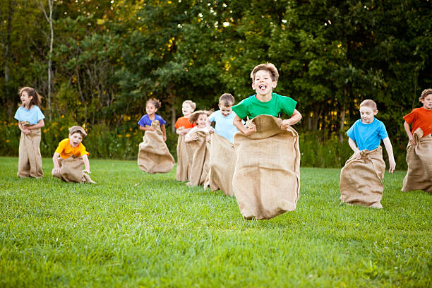 Happy Children Having a Fun Potato Sack Race Outside stock photo