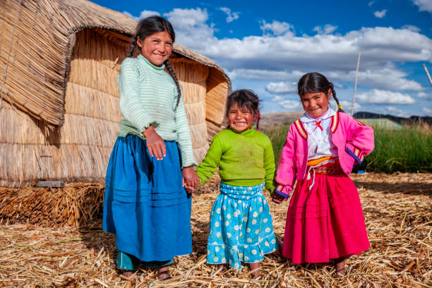 Happy children on Uros floating island, Lake Tititcaca, Peru Little kids having fun on Uros floating island. Uros are a pre-Incan people that live on forty-two self-fashioned floating island in Lake Titicaca Puno, Peru and Bolivia. They form three main groups: Uru-Chipayas, Uru-Muratos  and the Uru-Iruitos. The latter are still located on the Bolivian side of Lake Titicaca and Desaguadero River. The Uros use bundles of dried totora reeds to make reed boats (balsas mats), and to make the islands themselves. The Uros islands at 3810 meters above sea level are just five kilometers west from Puno port. peru girl stock pictures, royalty-free photos & images