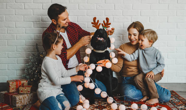 vrolijk kerstmis! familie moeder vader en kinderen met hond voor kerstmis met garland en boom - hondachtige stockfoto's en -beelden