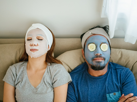Happy time, couple applying facial mask during coronavirus quarantine at home.