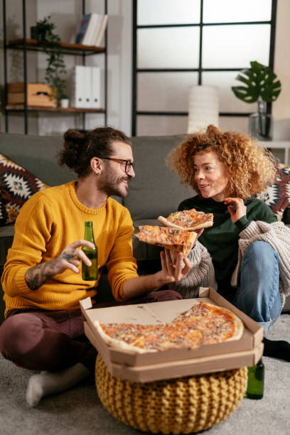 Happy couple drinking beer and eating pizza, spending time together at home stock photo stock photo