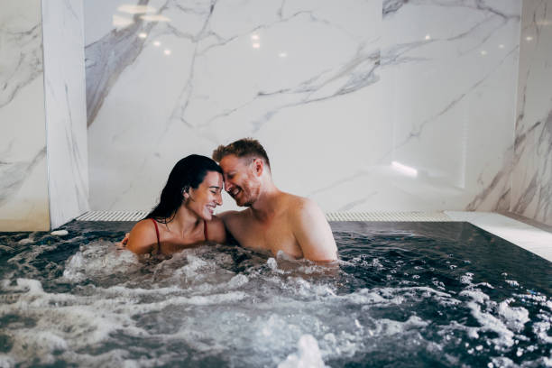happy couple having fun in hot tub - jacuzzi stockfoto's en -beelden