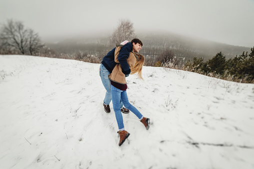 Happy Couple Having Fun Time Outdoors In Snow Park Winter