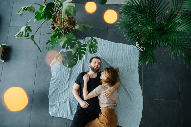coppia felice sdraiata sul pavimento sotto rami di piante - floor top view foto e immagini stock