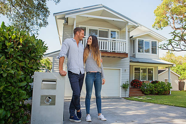 happy couple standing by mailbox in front of home stock photo