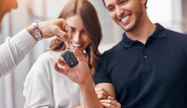 Happy couple taking car keys from manager stock photo