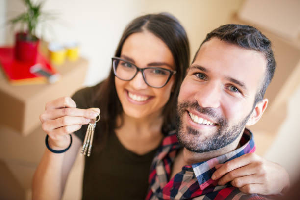 Happy couple taking selfie with keys of new home stock photo