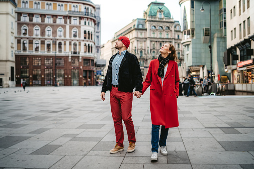 Romantic couple is walking over town square in Vienna, holding hands.