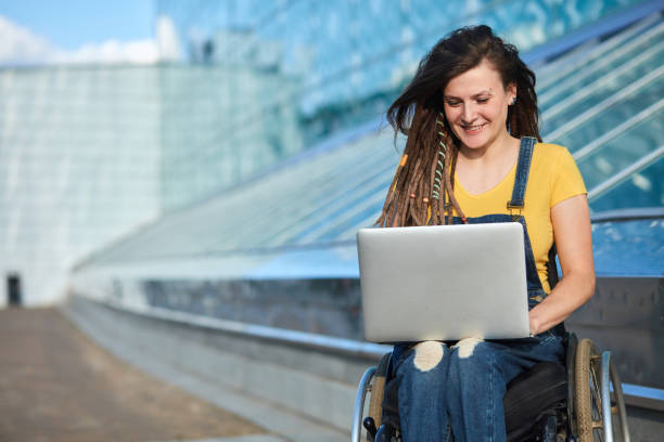 happy cute businesswoman in wheelchair working using a laptop - wheelchair street happy imagens e fotografias de stock