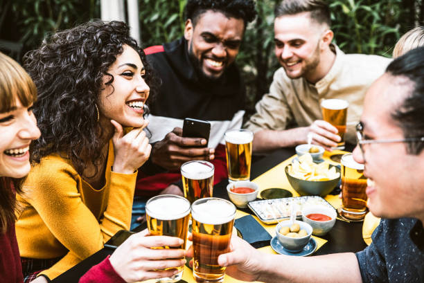 Happy diverse friends drinking beer at brewery pub - Group of young people having fun together at backyard home party - Friendship concept stock photo