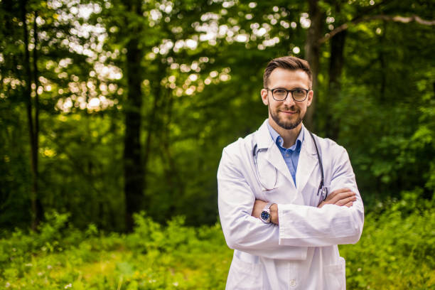 Happy doctor in nature looking at camera. stock photo