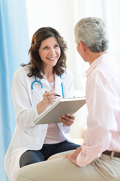 Happy Doctor With Clipboard Looking At Patient stock photo