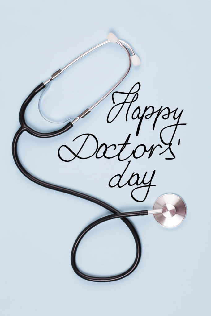 Stethoscope and text Happy Doctors' Day on blue background