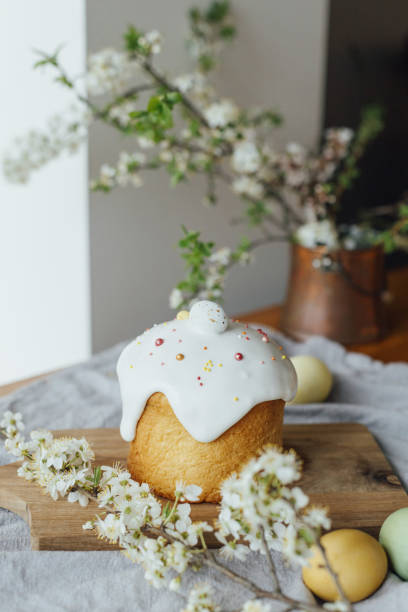 Happy Easter!  Homemade easter bread, natural dyed eggs and spring blossom on rustic table in room. Stylish freshly baked easter cake with sugar glaze and sprinkles, traditional ukrainian bun stock photo