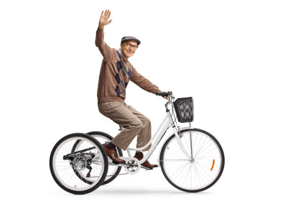 Happy elderly man riding a tricycle and waving at camera Happy elderly man riding a tricycle and waving at camera isolated on white background adult tricycle stock pictures, royalty-free photos & images