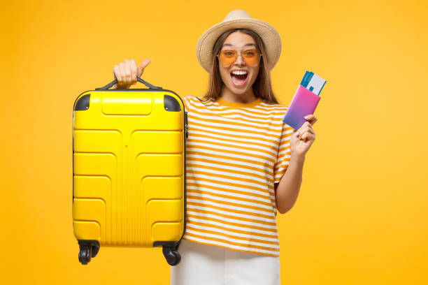 happy european girl with suitcase and airplane tickets isolated on yellow background excited about trip - happy traveling imagens e fotografias de stock