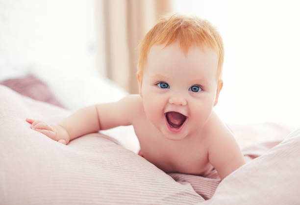 glücklich aufgeregt baby baby mädchen kriechen auf dem bett - weibliches baby stock-fotos und bilder