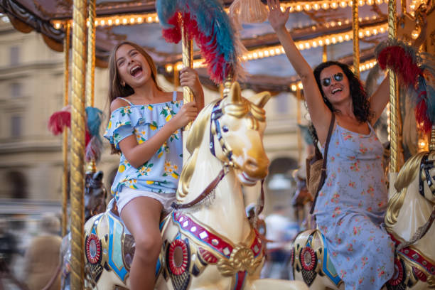 Happy family (mother and daughter) at the carousel. Merry too round horse Merry go round horse with colorful lights carousel horses stock pictures, royalty-free photos & images
