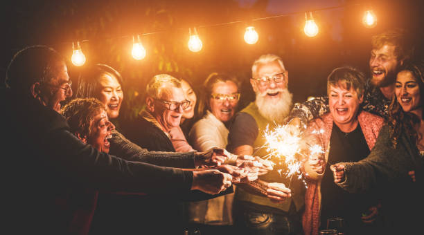Happy family celebrating with sparkler fireworks on new year's eve - Different age of people having fun together in patio party - Celebration, winter and holidays concept - Focus on left hands  holidays and celebrations stock pictures, royalty-free photos & images