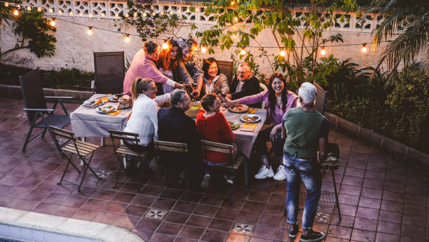 happy family eten en juichen met rode wijn op barbecue party dinner-verschillende leeftijd van mensen die plezier hebben op bbq maaltijd zittend in villa achtertuin-zomer lifestyle en food concept-focus op gezichten - family garden,party stockfoto's en -beelden