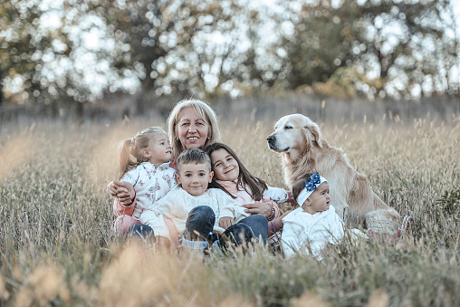 Happy family relaxing with their golden retriever and Bernese mountain dog