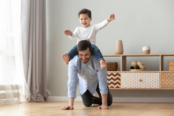 gelukkig familie opgewonden jongetje spelen met vader thuis - piggyback funny stockfoto's en -beelden