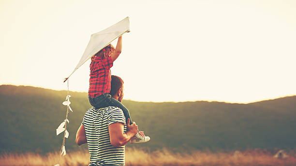 happy family father and child on meadow with a kite happy family father and child on meadow with a kite in the summer on the nature carrying photos stock pictures, royalty-free photos & images
