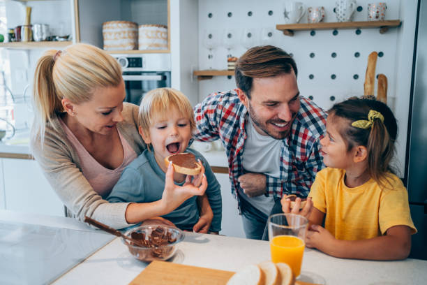Happy family having breakfast. Cheerful family having breakfast together in kitchen at home. couple eating chocolate stock pictures, royalty-free photos & images