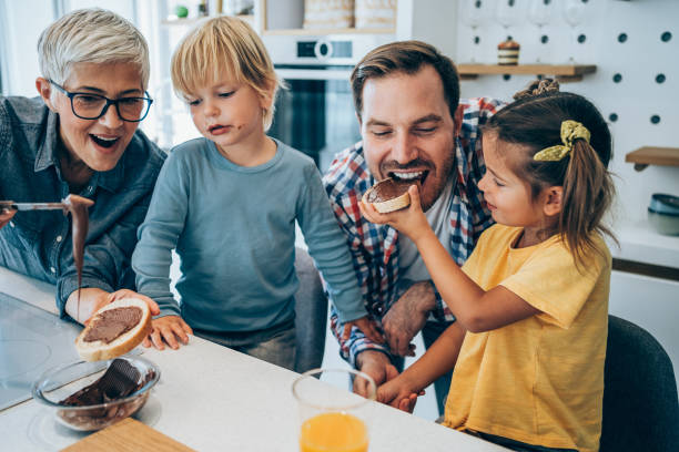 Happy family having breakfast. Three generation family having breakfast together in kitchen at home. couple eating chocolate stock pictures, royalty-free photos & images