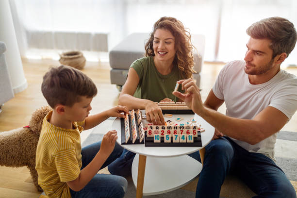 Happy family having fun, playing board game at home stock photo