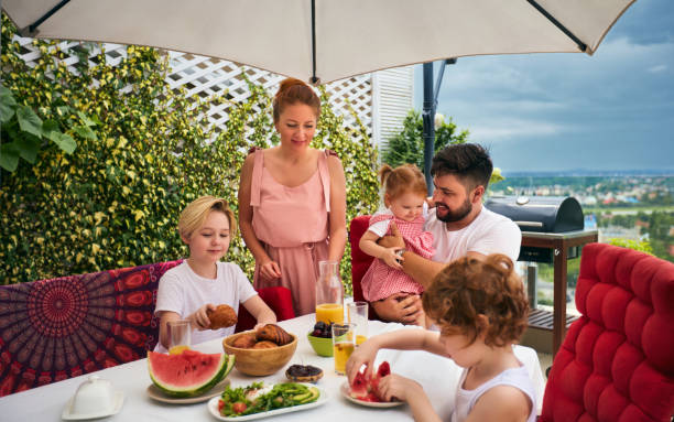 happy family having lunch on rooftop patio at home stock photo