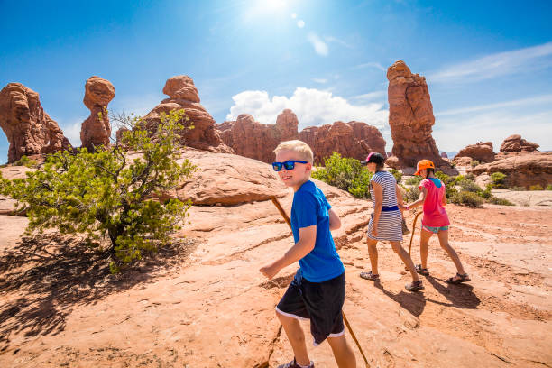 Happy family hiking together in the beautiful rock formations of Arches National Park A happy family hiking together in the beautiful rock formations of Arches National Park. Walking along a scenic trail with large rock unique formations in the background arches national park stock pictures, royalty-free photos & images