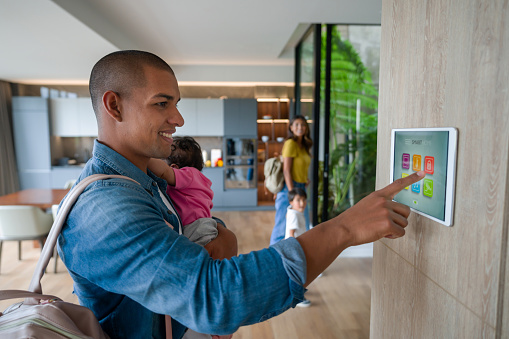 Happy Latin American family leaving the house locking the door using a home automation system - smart home concepts. **DESIGN ON SCREEN BELONGS TO US**