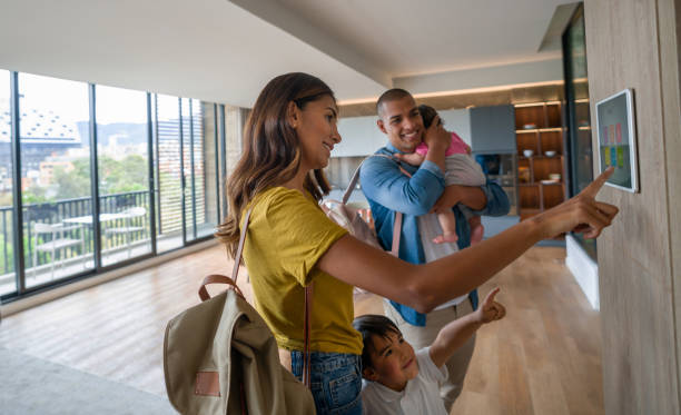 glückliche familie, die das haus verlässt und die tür mit einem automatisierten sicherheitssystem verriegelt - smart home stock-fotos und bilder