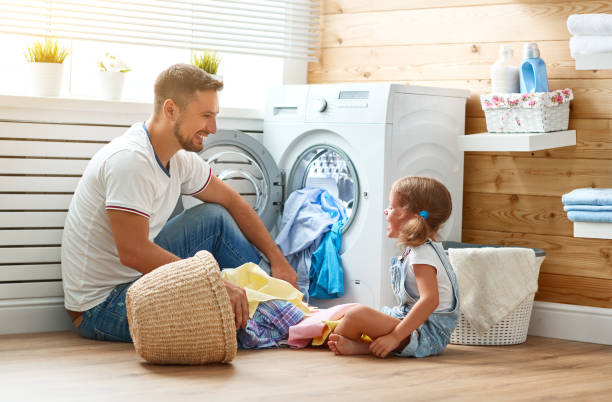 glückliche familie mann vater haushaltsvorstand und kind im waschraum mit waschmaschine - waschen stock-fotos und bilder