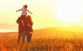 Happy family: mother father and child daughter on nature  on sunset