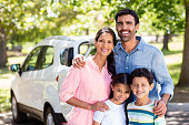 Portrait of happy family on a picnic standing next to their car