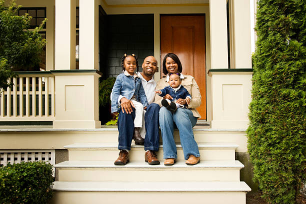 Happy Family on Front Porch Portrait of a young family sitting on the steps in front of their house. in front of stock pictures, royalty-free photos & images