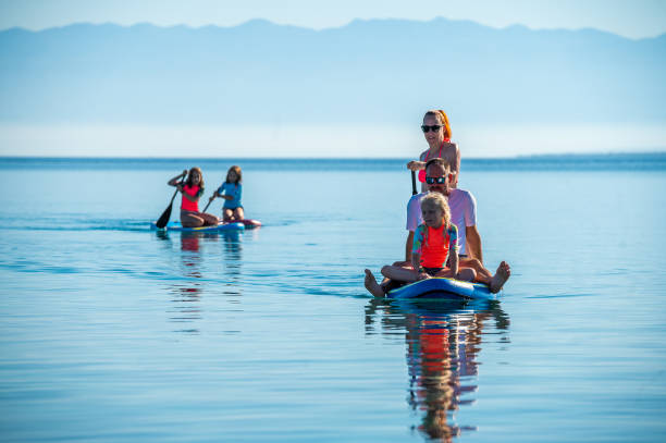 Happy Family on SUP stand up paddle on vacation. stock photo