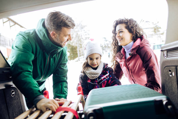 glückliche familie packt ihren kofferraum für den winterurlaub - auto packen für den urlaub winter stock-fotos und bilder