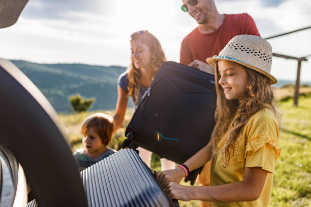 gelukkige familie die hun bagage in een autoboomstam inpakt. - packing suitcase stockfoto's en -beelden