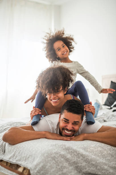 Happy family African american family playing in bed. bed furniture photos stock pictures, royalty-free photos & images