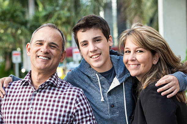 Happy family Smiling teenage boy posing with his parents in the background mother and teenage son stock pictures, royalty-free photos & images