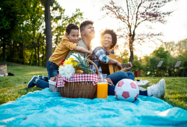 happy family play guitar and sing together while sitting in the park in summer. - picnic imagens e fotografias de stock