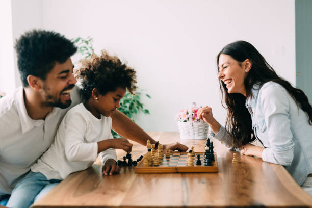 Happy family playing chess together at home Happy family playing chess together at their home board game photos stock pictures, royalty-free photos & images