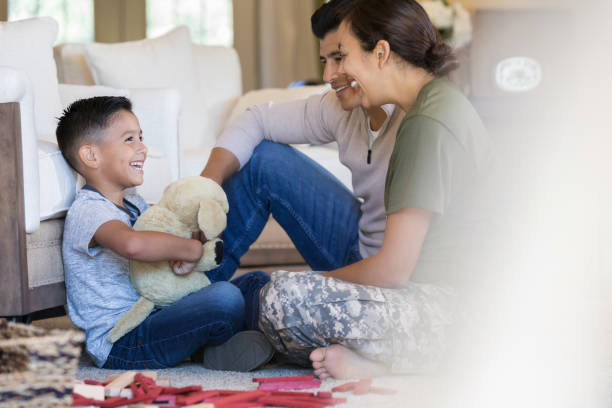 Happy family relaxing in their living room Happy female soldier smiles after a happy reunion with her husband and young son. She has returned home from military assignment. veterans returning home stock pictures, royalty-free photos & images