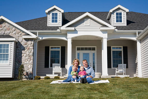 Happy family sit outside new houses on lawn posing for photo Happy Family in Front of Their Home in front of stock pictures, royalty-free photos & images