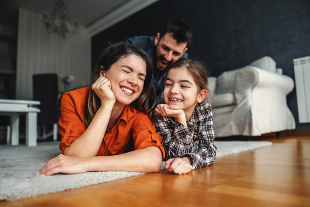 Happy family spending quality time together. They lying on the floor and laughing. stock photo