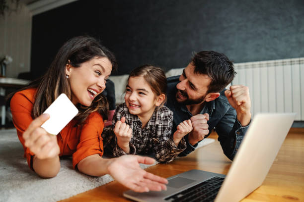 Happy family using laptop for online shopping. They are excited for purchase. Mom holding credit card. stock photo